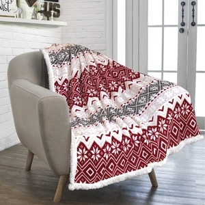 Red and white snowflake flannel Sherpa blanket draped on a chair in cozy home setting