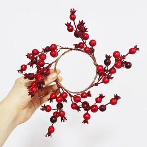Detailed close-up of a handmade red berry wreath with glossy pomegranate-like fruits