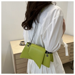 Detail of a neon green asymmetrical flap shoulder bag with a silver chain strap