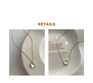 Detailed close-up of gold shell flower and round pendants on minimalist necklaces