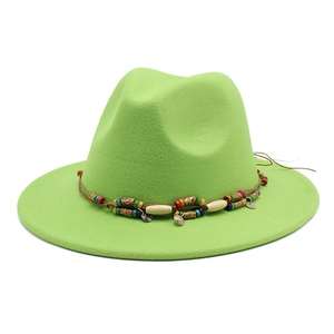 Détail d'un chapeau fedora vert néon avec corde tressée, perles colorées et pendentif