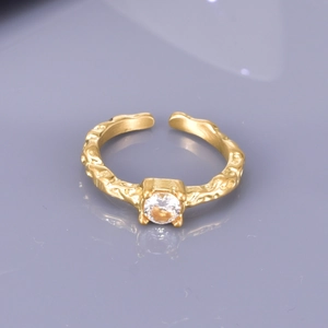 Close-up of golden open ring with irregular hammered texture and sparkling white zircon