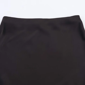 Gros plan détaillé montrant le tissu satiné lisse et les coutures de la jupe midi noire