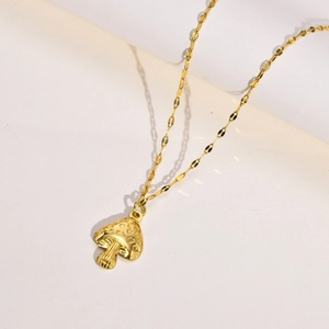 Macro detail of a 3D mushroom pendant necklace in polished gold with textured cap surface
