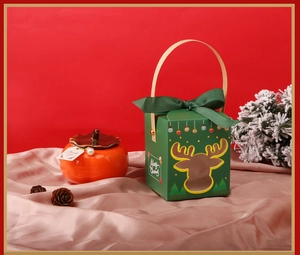 Macro detail of dark green deer-cutout Christmas gift box with orange ceramic persimmon jar