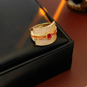 Detail of wide gold ring with emerald-cut red stone and pave white zircon on black leather