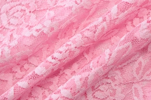 Gros plan sur un tissu en dentelle rose avec des motifs ajourés complexes et une texture douce