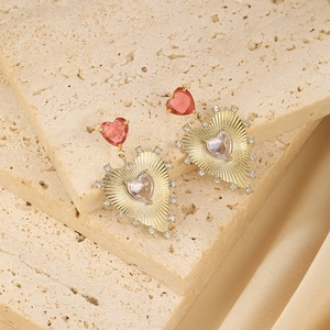 Macro view of gold-plated heart earrings with red tops and sparkling zircon stones
