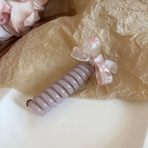 Gros plan d'un chouchou spirale violet avec nœud en résine sur papier brun