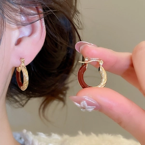 Detail of vintage twisted gold hoop earrings with deep reddish-brown enamel inlay