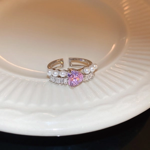 Détail de la bague argentée avec zircon cœur rose, perles et pierres de type baguette