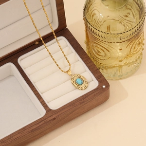 Vintage gold stainless steel necklace featuring an oval turquoise stone pendant in a wooden box