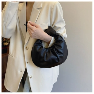 Detail of minimalist black pleated leather crescent handbag with elegant handle design