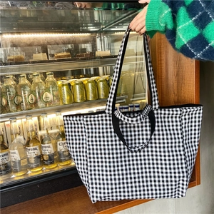 Detail of a large capacity black and white checkered canvas tote bag with wide strap