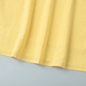 Detail of lemon yellow ruffled hemline with premium stitching and breathable fabric texture