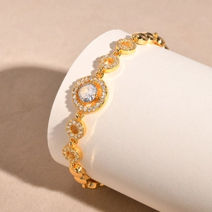 Macro shot of gold-plated bracelet with zircon centerpiece on white display stand