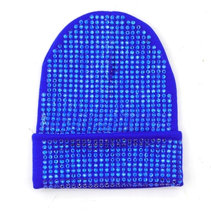 Dettaglio di un berretto in maglia blu reale con strass blu densamente incastonati sul tessuto