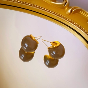Vue macro de boucles d'oreilles en résine ambre et bordure en métal doré liquide