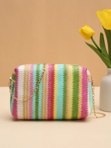 Detail of colorful woven crossbody bag featuring vibrant V-shaped stripes and gold chain strap