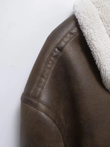 Detail of brown faux suede jacket featuring white faux shearling collar and shoulder seams