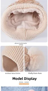 Detail view of winter knitted hat featuring thick fleece lining and fluffy faux fur pompom