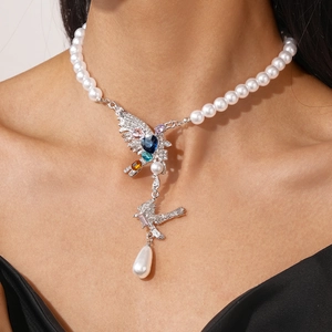 Close-up of bird pendant necklace with colorful crystals and teardrop pearl on model