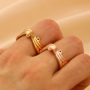 Close-up of gold and rose gold wave rings with bead details on silk fabric