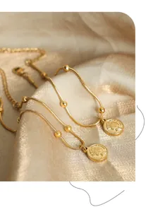 Close-up of vintage gold coin pendant on snake chain bracelet over luxury silk