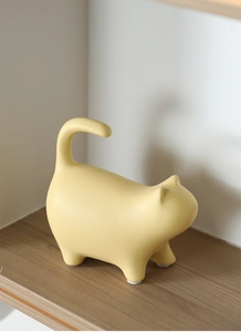 Detail view of yellow ceramic cat figurine with smooth lines and non-slip pads on base