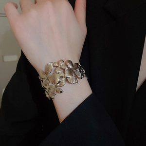 Gros plan d'un bracelet manchette à pétales avec texture métallique dorée brossée