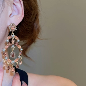 Close-up of dangling drop earrings with champagne stones and pearls on a model