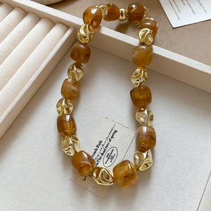 Close-up of irregular amber resin and golden textured metal beads on a beaded bracelet