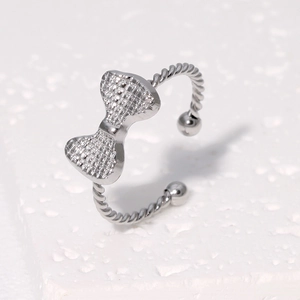 Minimalist silver bow open ring with textured rope band on white stone background