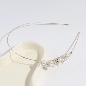 Detail of gold metal headband with white faux pearls and rhinestone star on ceramic tray
