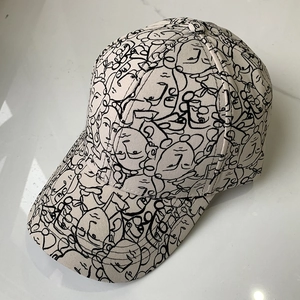 Off-white baseball cap with black abstract face art print on a marble background