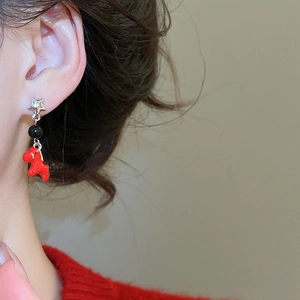 Detail of star-shaped silver earring with red horse pendant on a female model