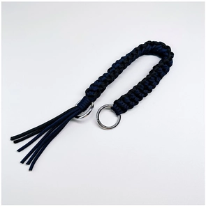 Detail of hand-woven dark blue and black nylon bag strap with metal rings and tassels