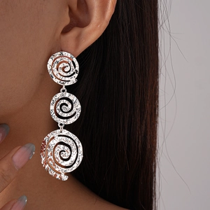 Gros plan de boucles d'oreilles pendantes argentées avec trois disques de métal spiralés
