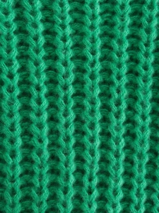 Vista macro del tessuto a maglia a coste verde smeraldo del maglione da donna