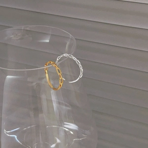 Close-up of gold and silver chain link rings hanging on glass rim with shadow background