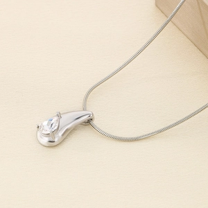 Detail of silver snake chain with teardrop crystal pendant on textured background