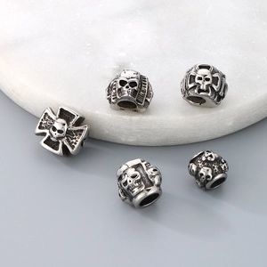 Detailed view of five vintage titanium steel skull beads on a marble tray