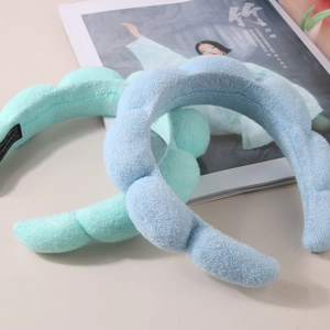 Close-up of thick mint green and light blue terry cloth padded spa headbands on a magazine