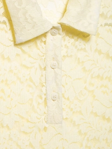 Detailed macro view of the lace collar and round buttons on this yellow polo shirt