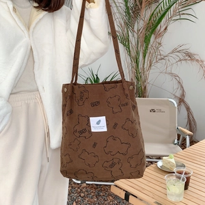 Brown corduroy tote bag with bear print shown in a lifestyle outdoor camping setting