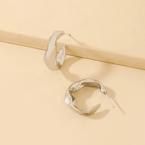 Macro shot of irregular C-shaped liquid metal silver earrings with high polish texture