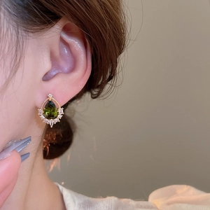 Nahaufnahme eines 18k vergoldeten Tropfenohrrings mit grünem Zirkon an einem Model