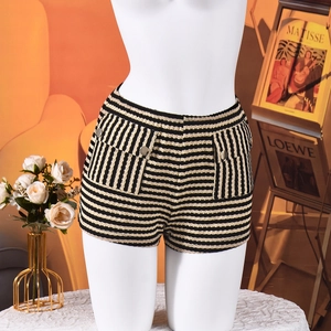 Detailopname van zwart-gouden gestreepte tweed shorts met decoratieve metalen knopen