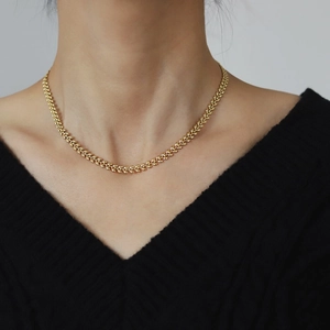 Close-up of golden wheat ear choker necklace on model with black V-neck top