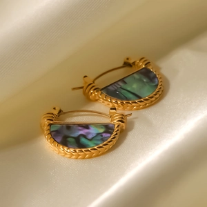 Macro-detail van vintage gouden oorringen met iriserende abalone schelp inleg